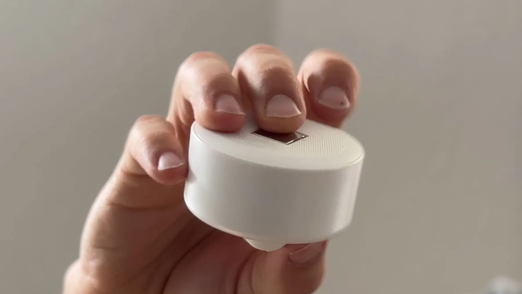 White sensor housing for thingdust held in a hand – final industrial design